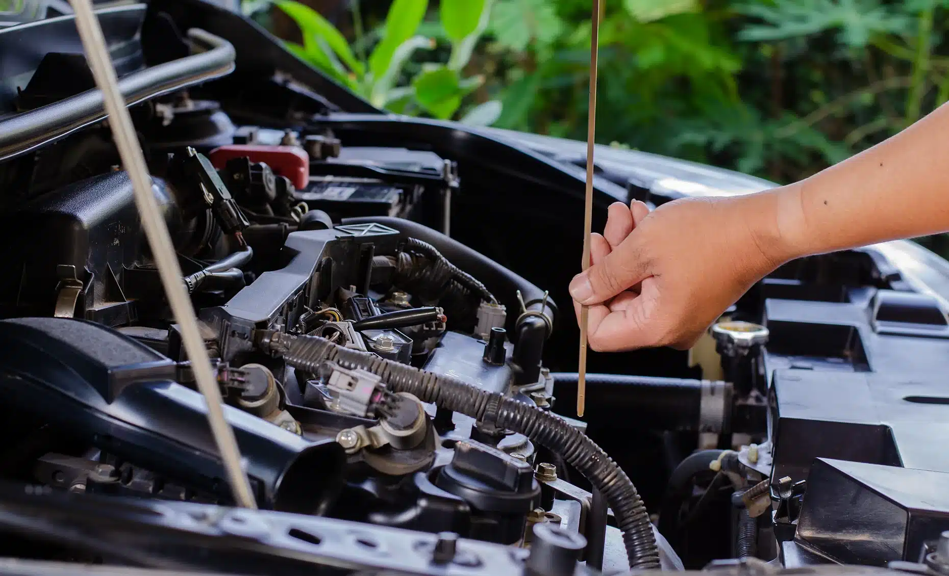 Full service auto repair in Albuquerque, NM by Albuquerque Auto Repair and Tire. Image of a technician checking engine oil with a dipstick, emphasizing preventive maintenance and performance.