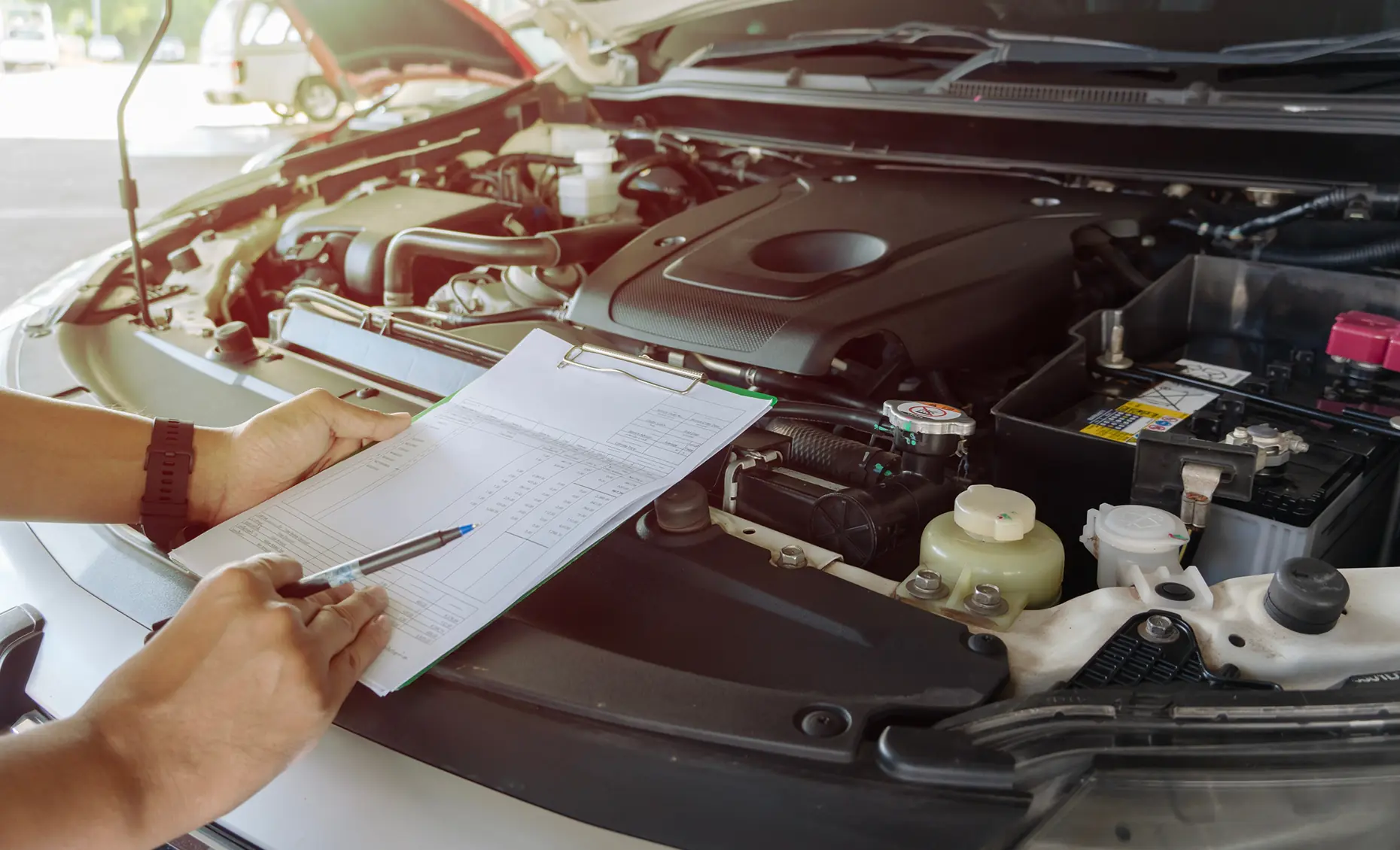 Preventative maintenance in Albuquerque, NM by Albuquerque Auto Repair and Tire. Image of a technician reviewing a checklist beside an open engine, emphasizing safety and maintenance accuracy.