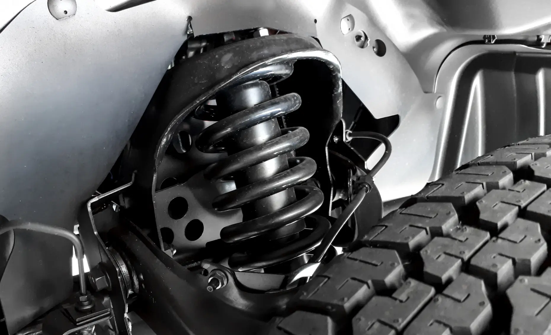 Steering and suspension repair in Albuquerque, NM by Albuquerque Auto Repair and Tire. Image of a close-up suspension spring and tire, showcasing durability and commitment to safe vehicle handling.
