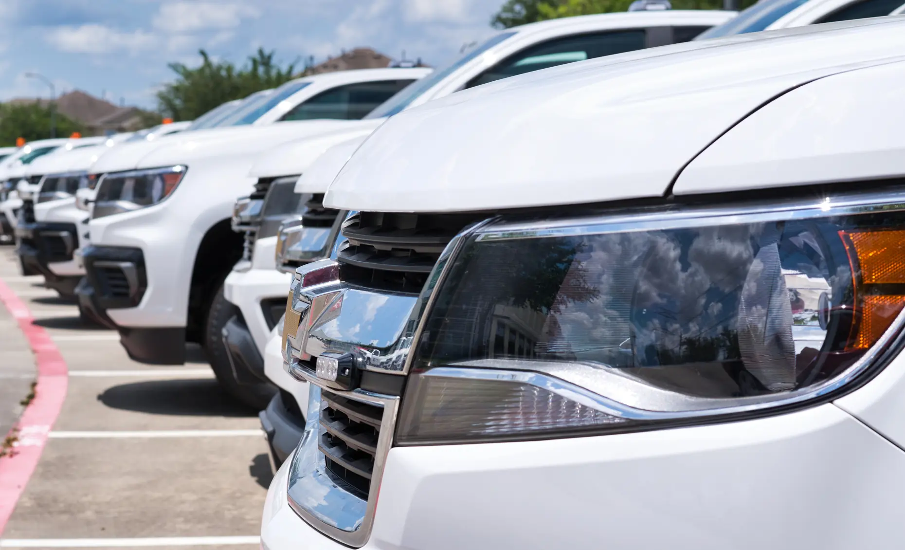 Fleet maintenance in Albuquerque, NM by Albuquerque Auto Repair and Tire. Image of a lineup of white service vehicles parked in a row, reflecting reliability and professional upkeep.