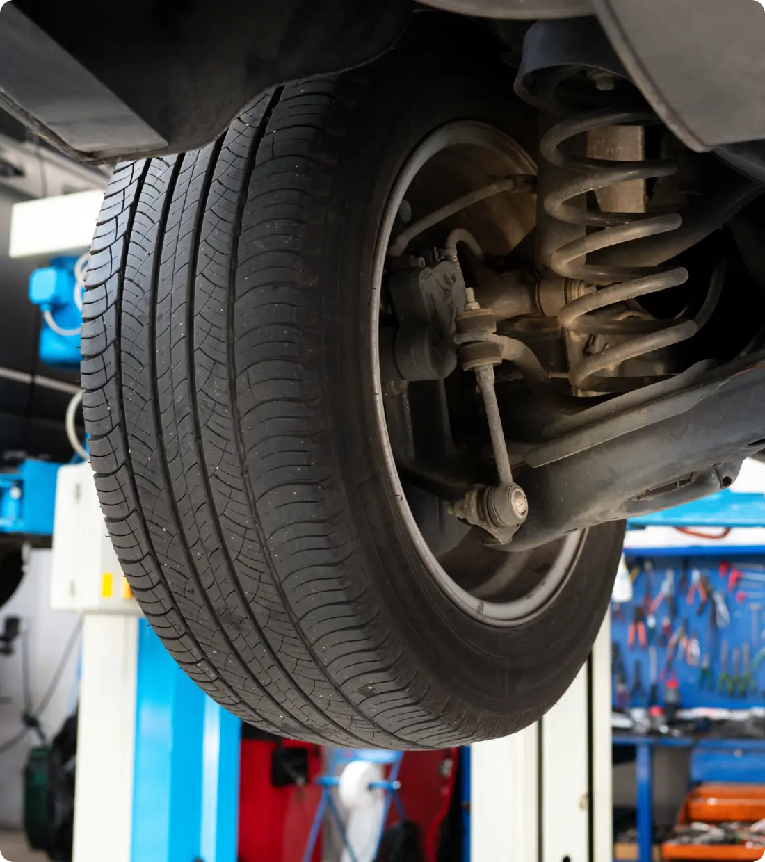 An image of a car on a lift undergoing maintenance service.
