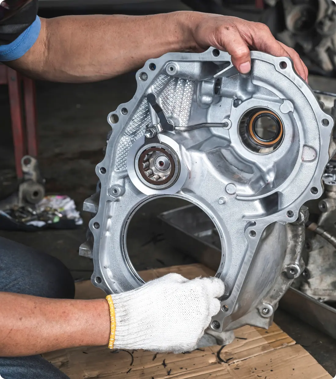 A mechanic holding a metallic engine part.