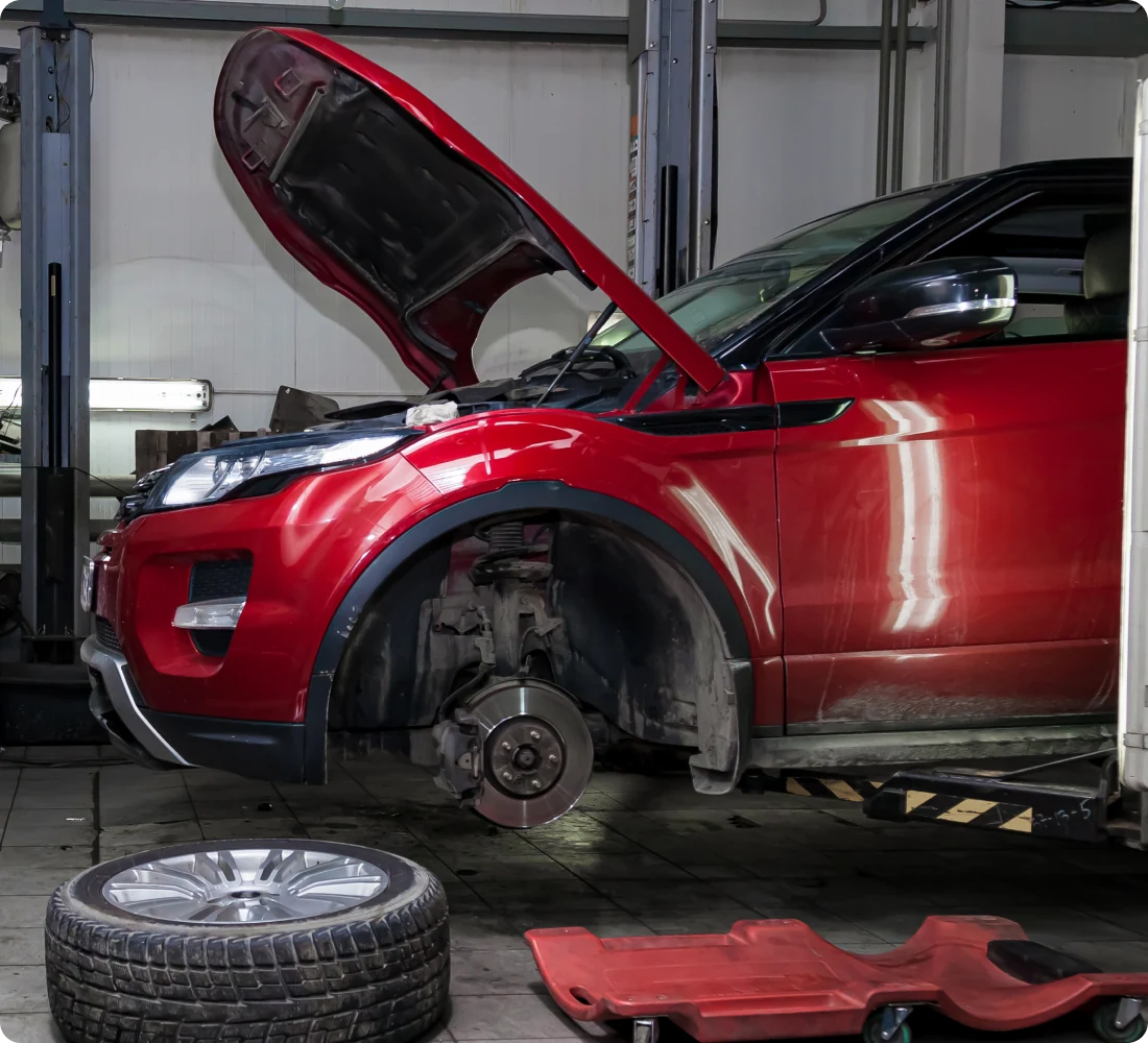 Red car with hood open, undergoing maintenance