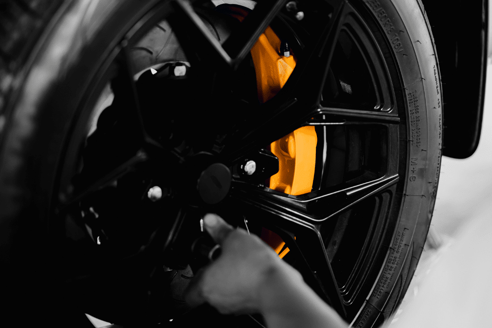 Tires and brake maintenance, auto repair in Albuquerque, NM by Albuquerque Auto Repair and Tire. Image of a technician working near a wheel with a bright yellow brake caliper. Highlighting the shop’s commitment to safety and precise brake performance for local drivers.