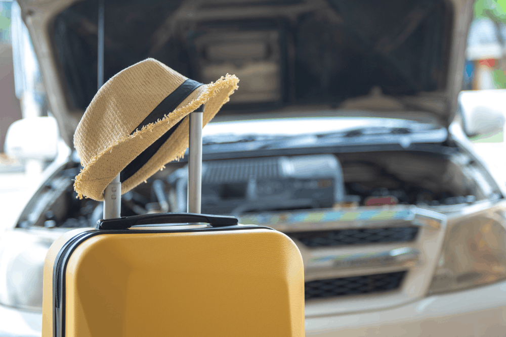 Vehicle inspection, auto repair in Albuquerque, NM at Albuquerque Auto Repair & Tire. Image of luggage beside a vehicle with the hood open, highlighting the importance of preventative maintenance and roadside breakdown prevention before travel.
